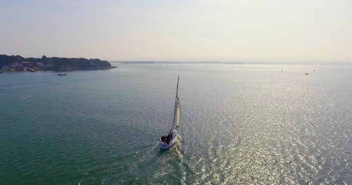 A boat sailing out from Poole Harbour past Sandbanks.