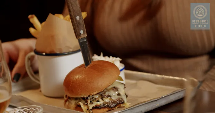 A freshly cooked burger and portion of fries being carried on a tray by a lady.