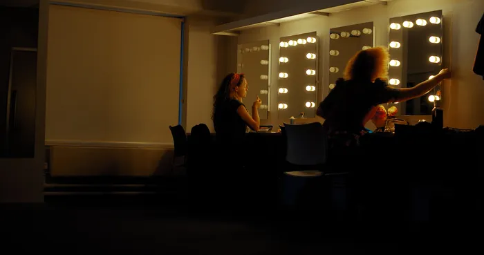 Two women getting ready in the dressing rooms of a theatre.